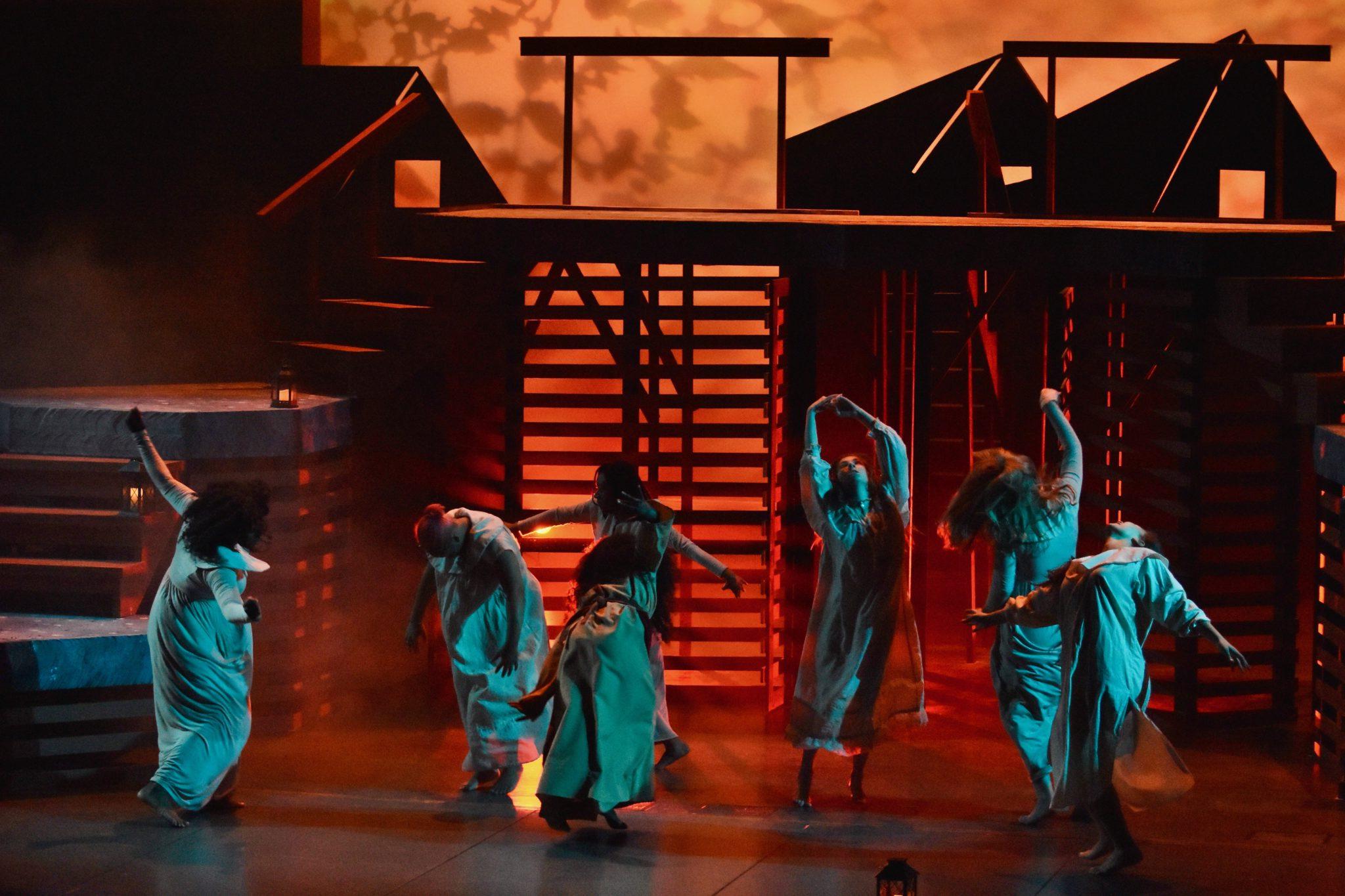 学生 dancing on stage in white attire during a performance of the Crucible